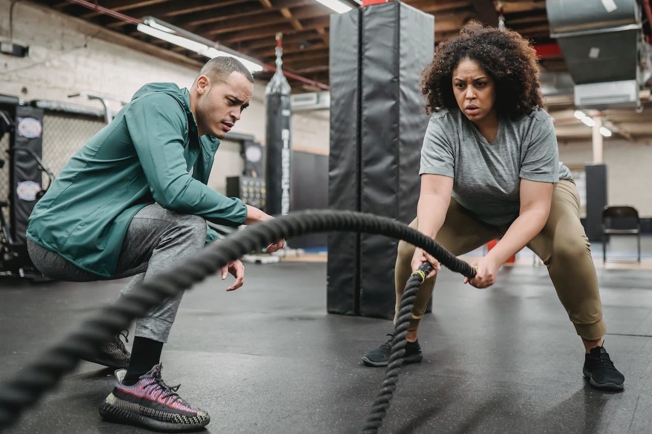 Fitnesstrainer coacht Frau beim Training